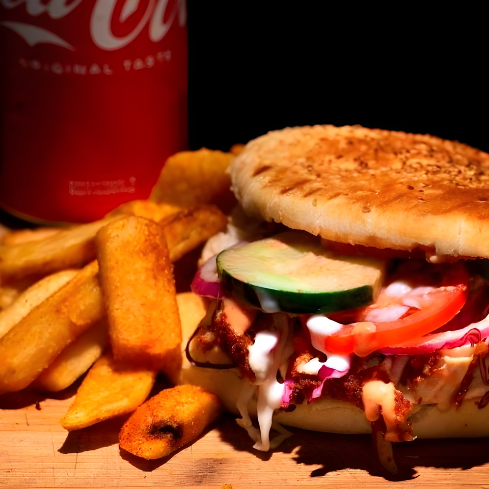 Baba's Kebab with fries and a Coca-Cola can on a wooden surface.
